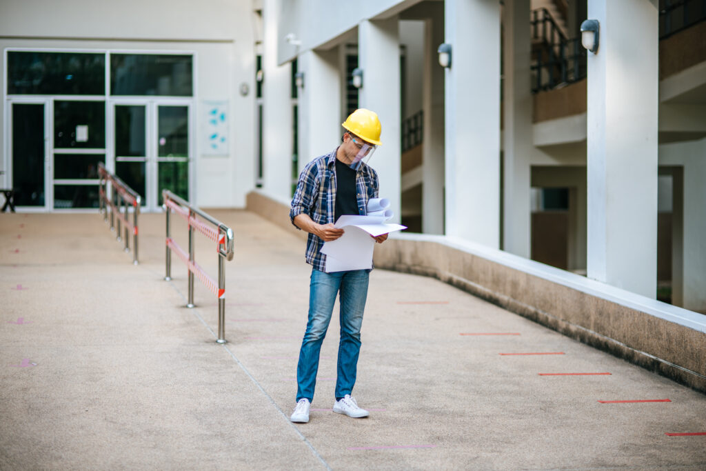 Recém-formado em engenharia civil analisando um projeto no canteiro de obras